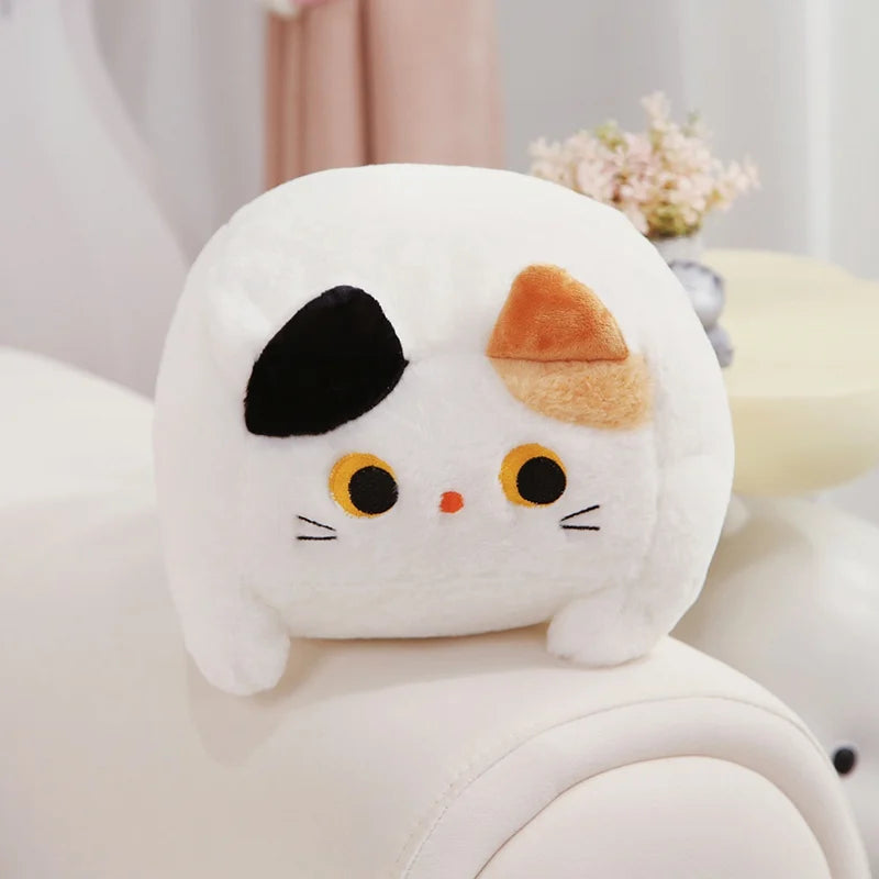 Kawaii plush toy resembling a cat with a white face and black and orange ears on a light background.