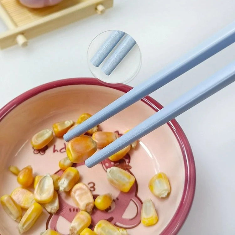 Pink bowl with corn kernels and blue kawaii chopsticks on a light background