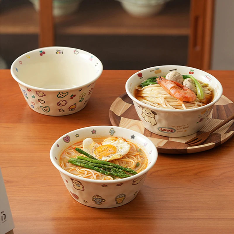 Three bowls of kawaii ramen bowls with decorative patterns on a wooden table.
