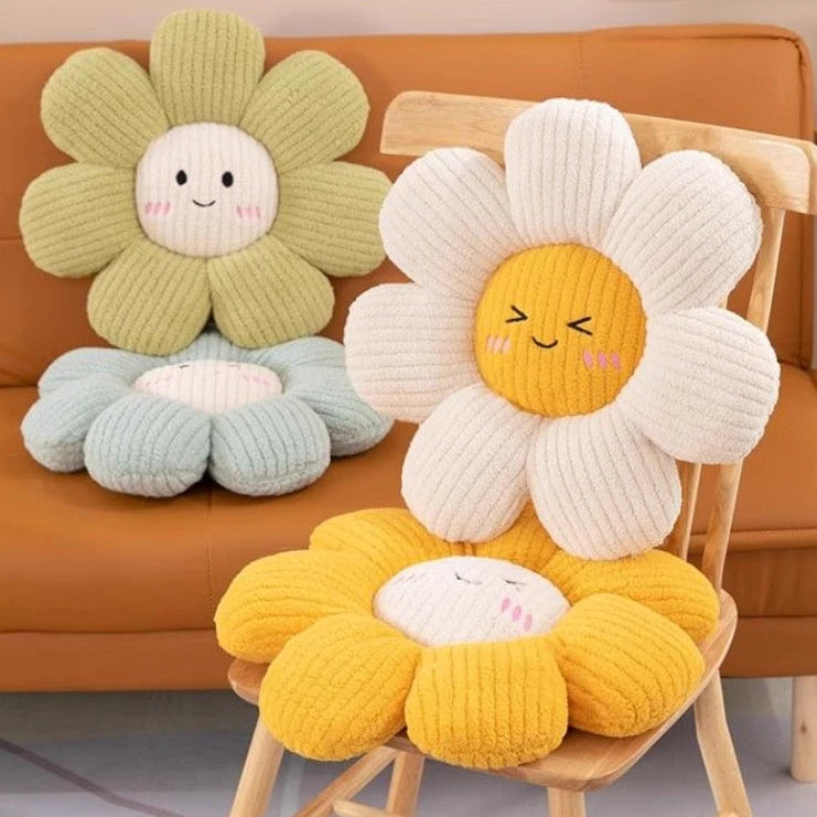 Three knitted flower-shaped kawaii cushions with smiling faces on a chair and couch.