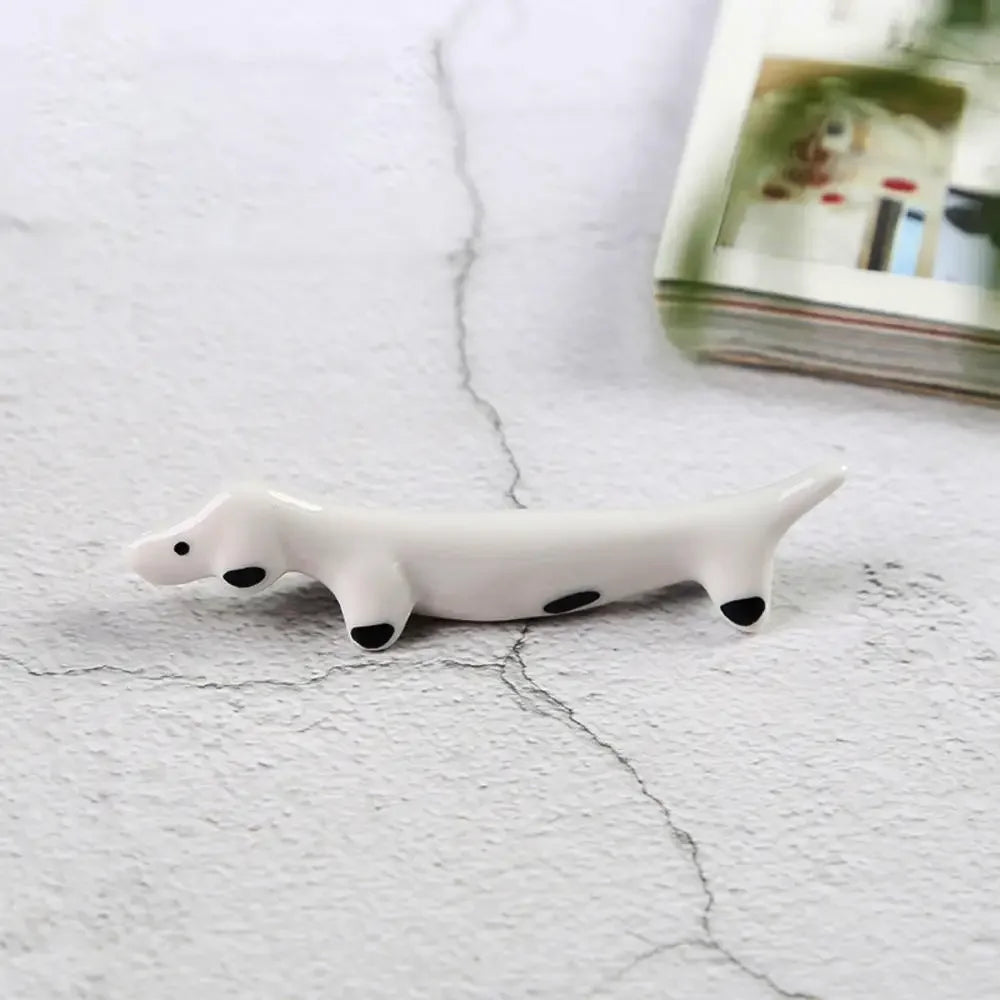 White ceramic seal kawaii chopstick holders on a textured white surface with a magazine in the background.