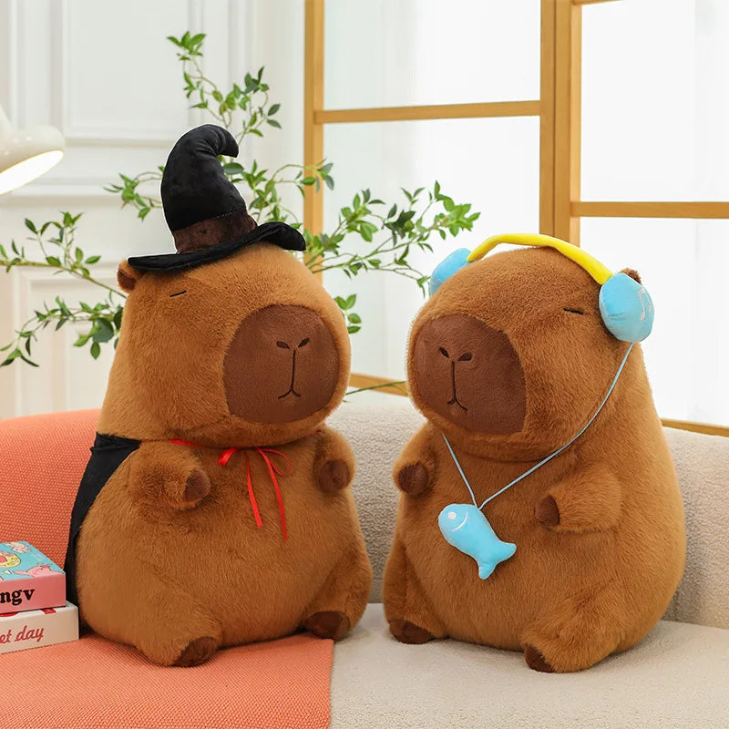 Two brown capybara plush toys with accessories on a couch