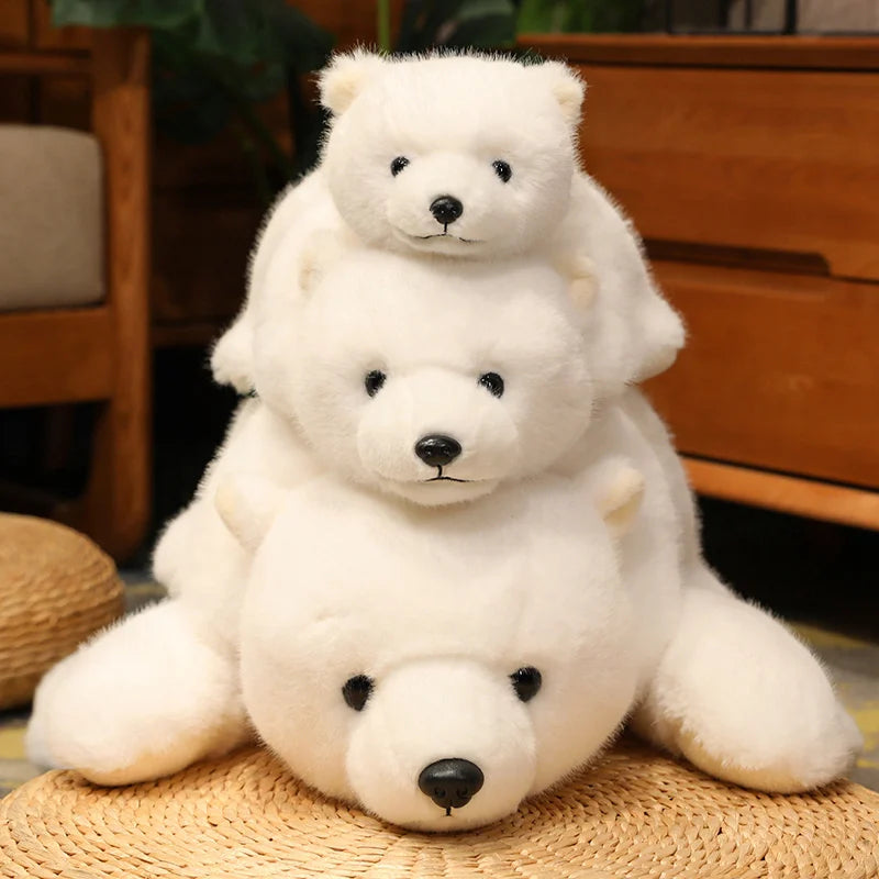 Three white kawaii teddy bears of different sizes stacked on a woven mat with a wooden cabinet in the background.