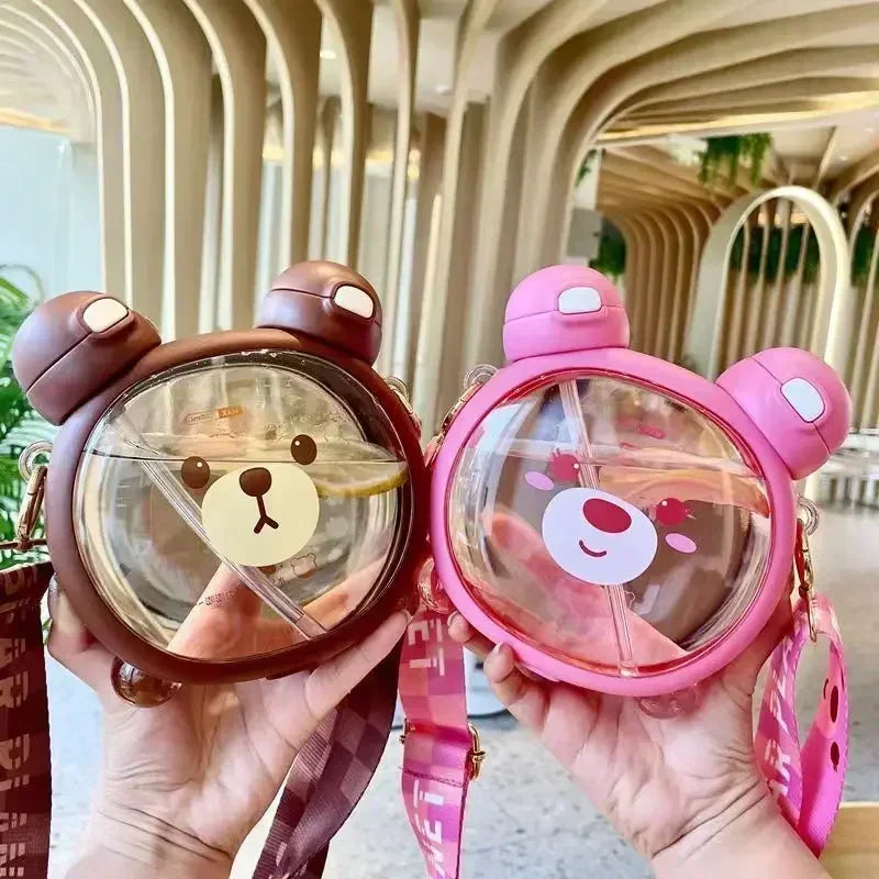 Two bear-shaped kawaii water bottles, one brown and one pink, held in hands with a blurred indoor background.