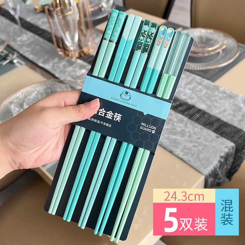 Pack of turquoise kawaii chopsticks held by a hand with a dining table in the background
