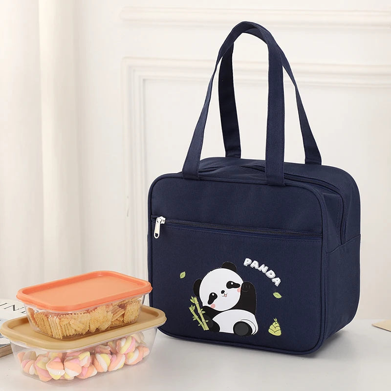 Navy blue insulated kawaii lunch bag with panda design next to a container of snacks on a light surface.