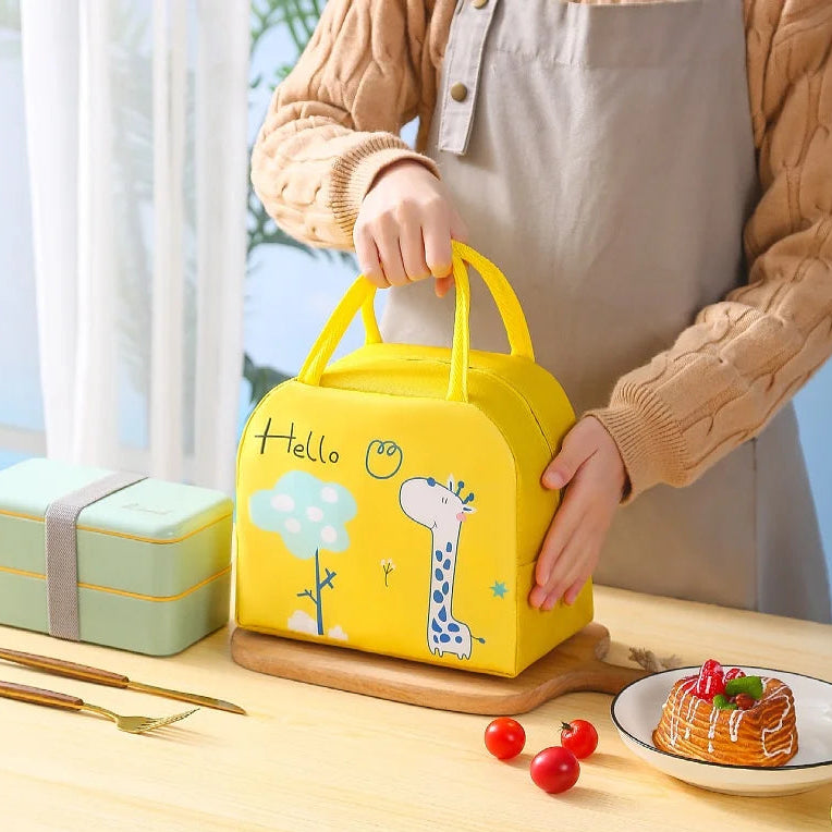 Person holding a yellow cartoon-themed kawaii lunch box on a table with a cake and cherries.