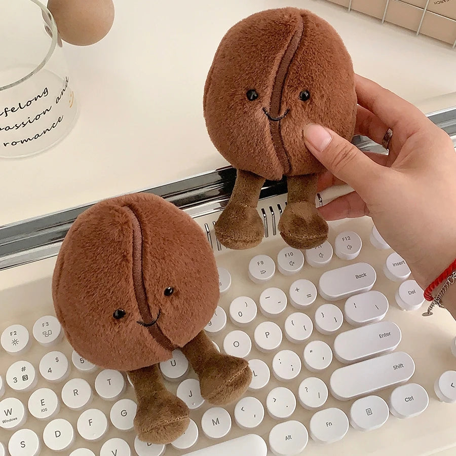 Two small brown kawaii plush toys resembling brain-shaped characters on a keyboard.