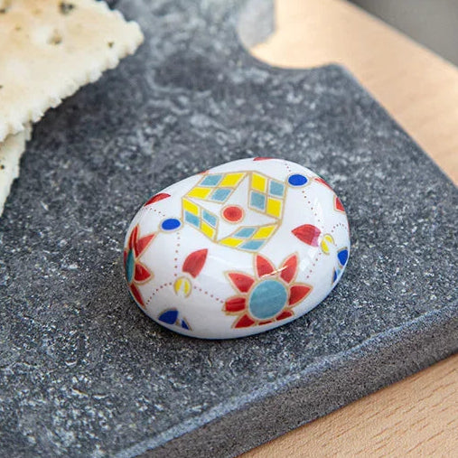 Decorative kawaii chopstick holder with colorful patterns on a gray surface