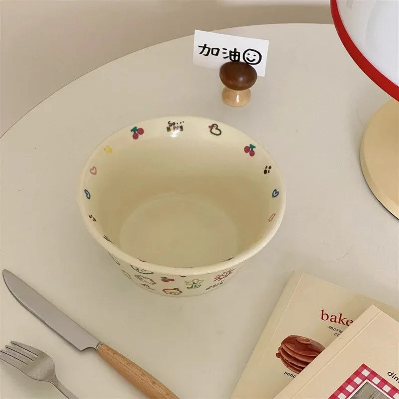 Small ceramic kawaii ramen bowl with decorative patterns on a kitchen counter with utensils and a book.