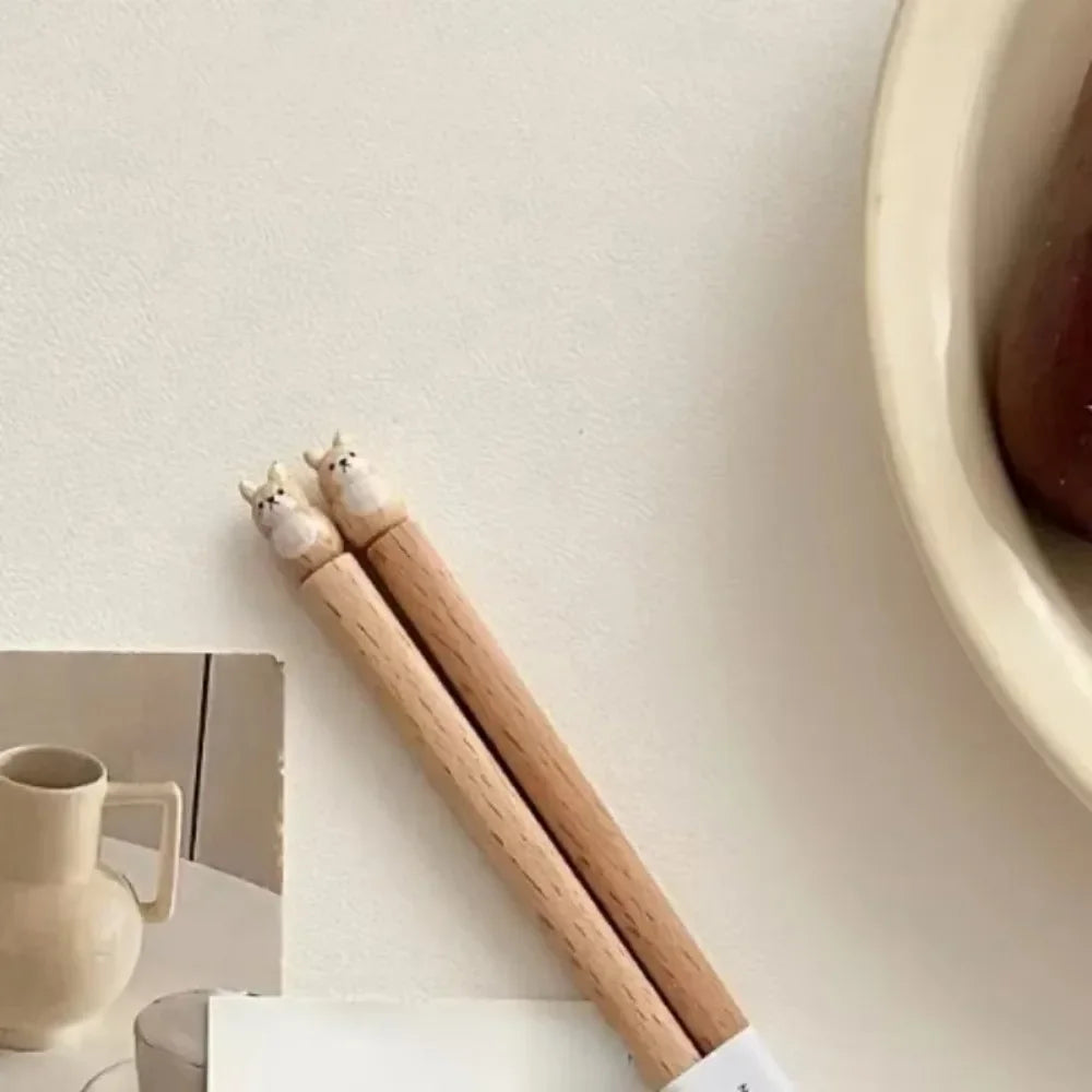 Wooden kawaii chopsticks with cat-shaped ends on a light surface