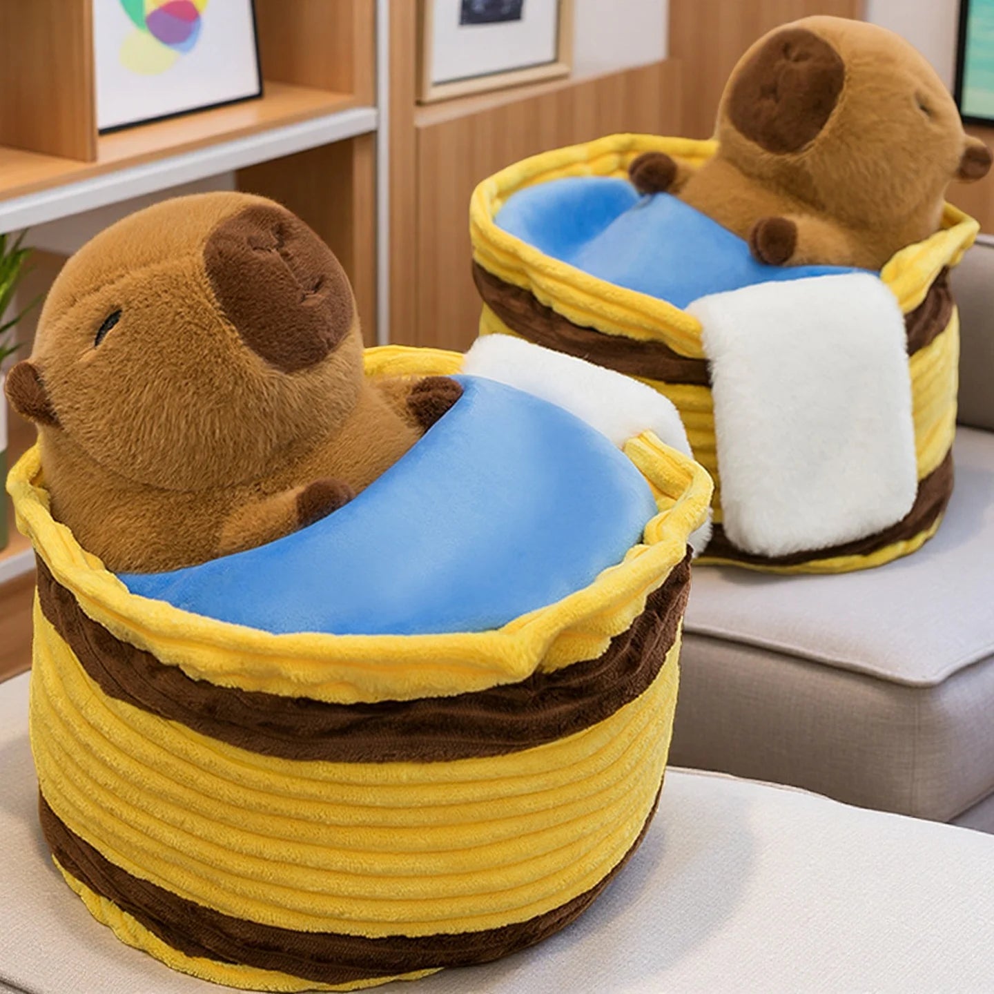 Two kawaii plush otters in yellow baskets with blue and white blankets on a couch.