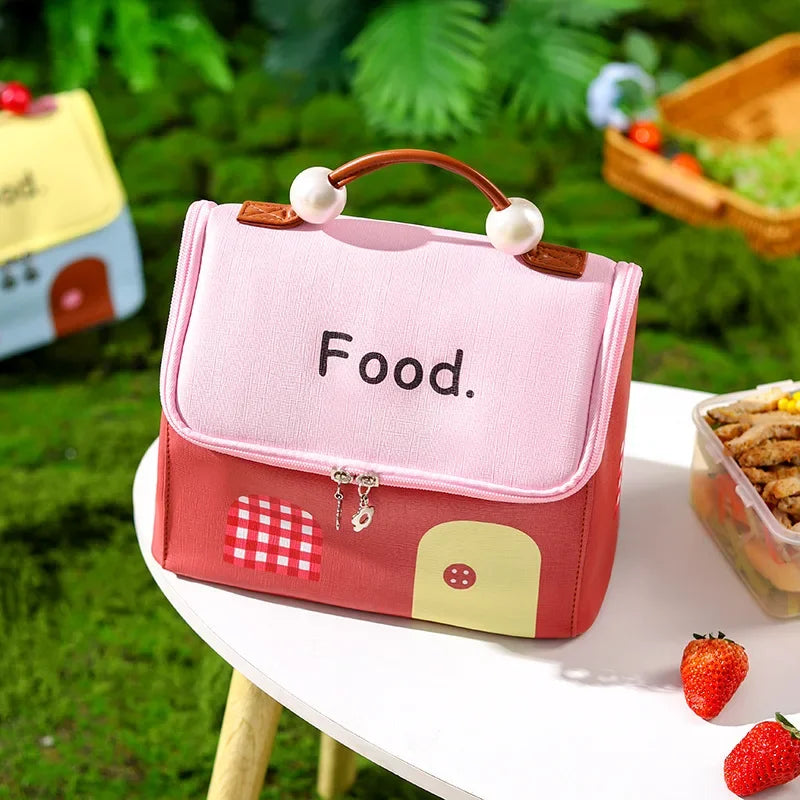 Pink and red kawaii lunch bag labeled 'Food' on a table outdoors with greenery in the background.