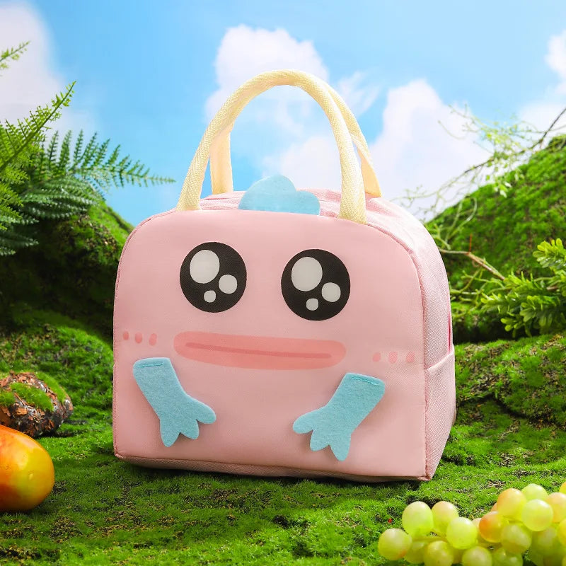 Pink cartoon-style kawaii lunch bag with frog design on a grassy background
