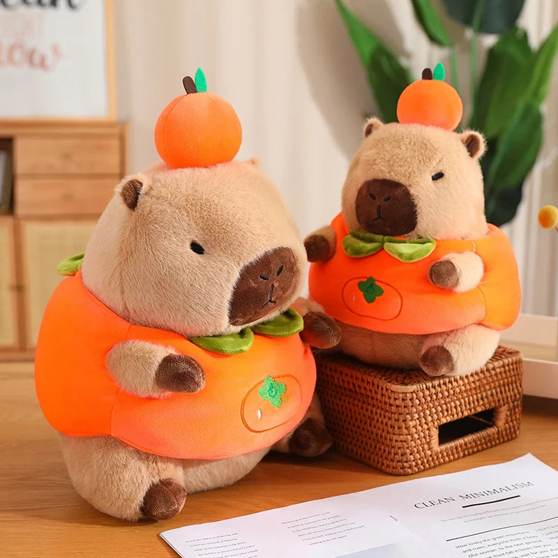 Two kawaii plush toys resembling beavers in pumpkin costumes on a wooden surface.