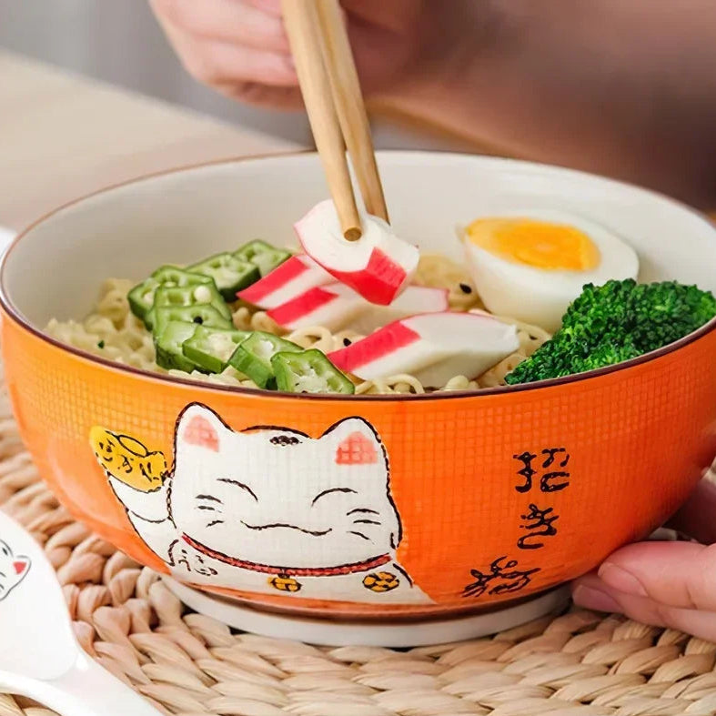 Orange kawaii bowl with a cat design containing noodles, vegetables, and a boiled egg.