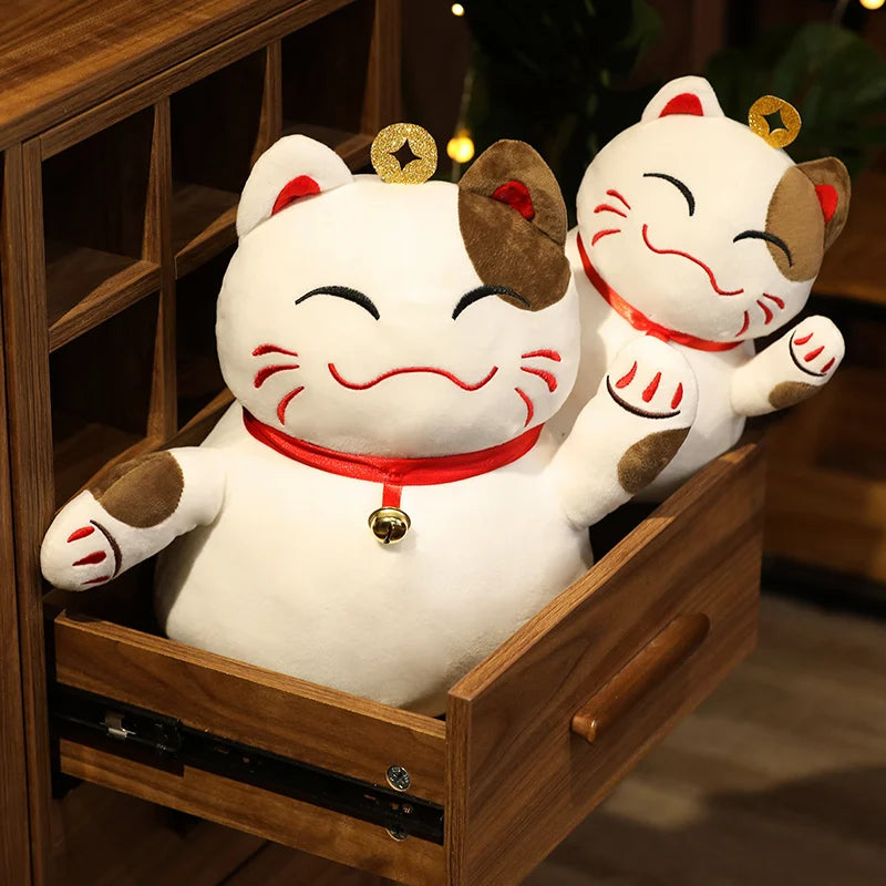 Two kawaii plush Maneki Neko cats in a wooden drawer with a blurred background