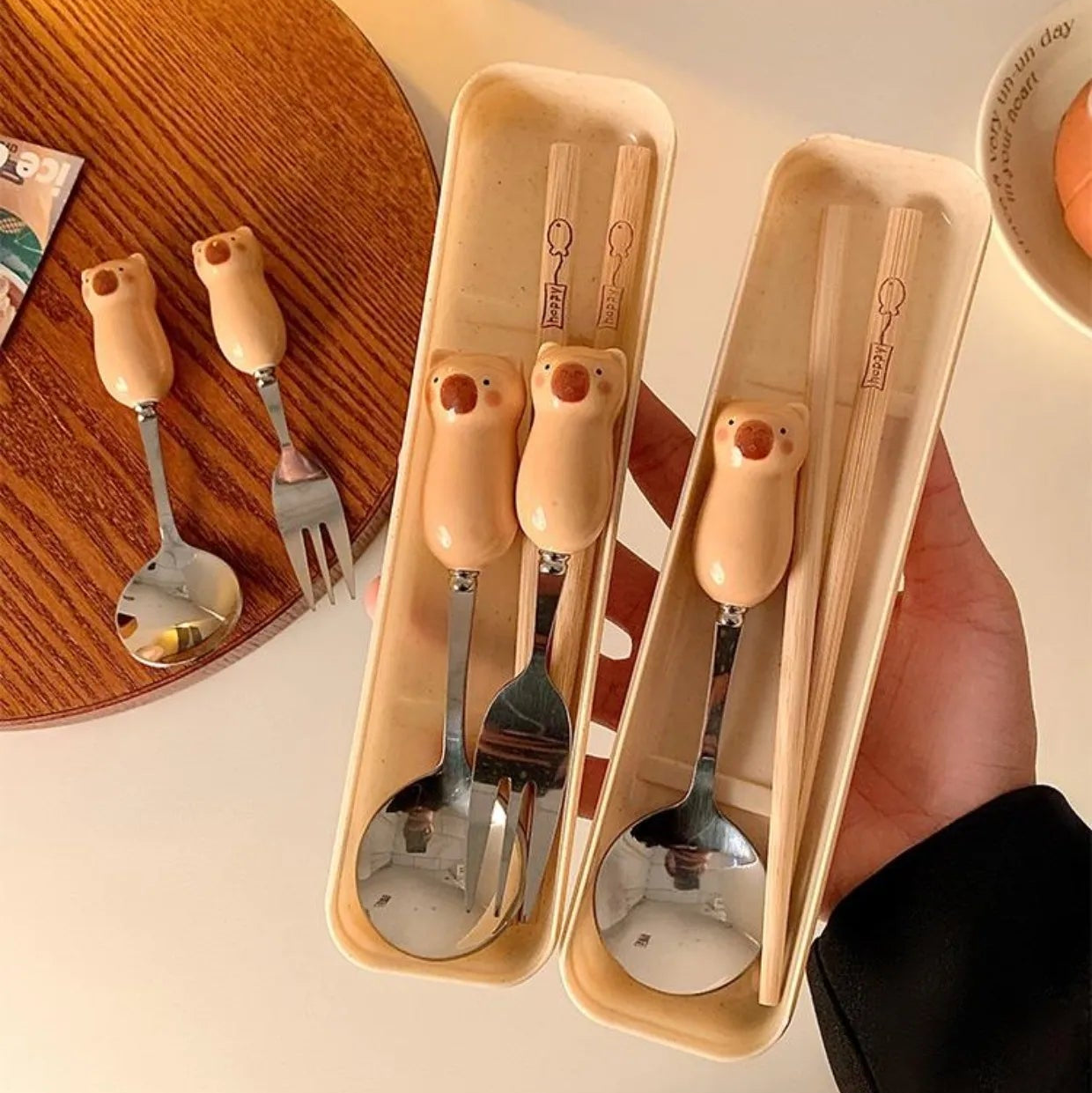 Set of kawaii utensils including spoons and forks in a beige holder on a wooden table.