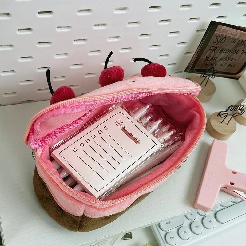 Pink pouch with kawaii cherry design containing stationery items on a desk.