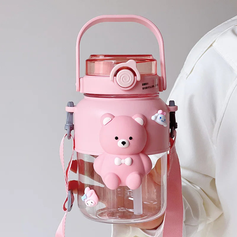Pink kawaii water bottle with bear design and strap on a light gray background