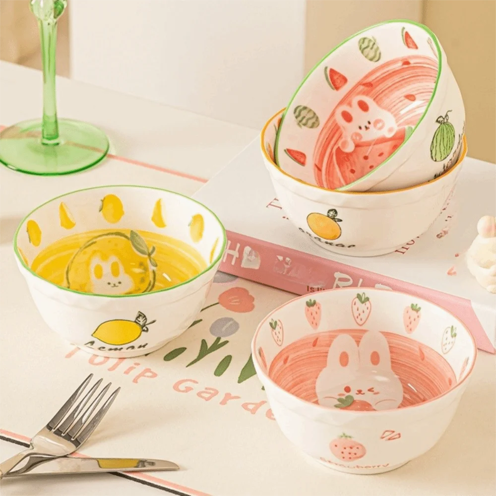 Set of ceramic kawaii ramen bowls with cute animal and fruit designs on a table.