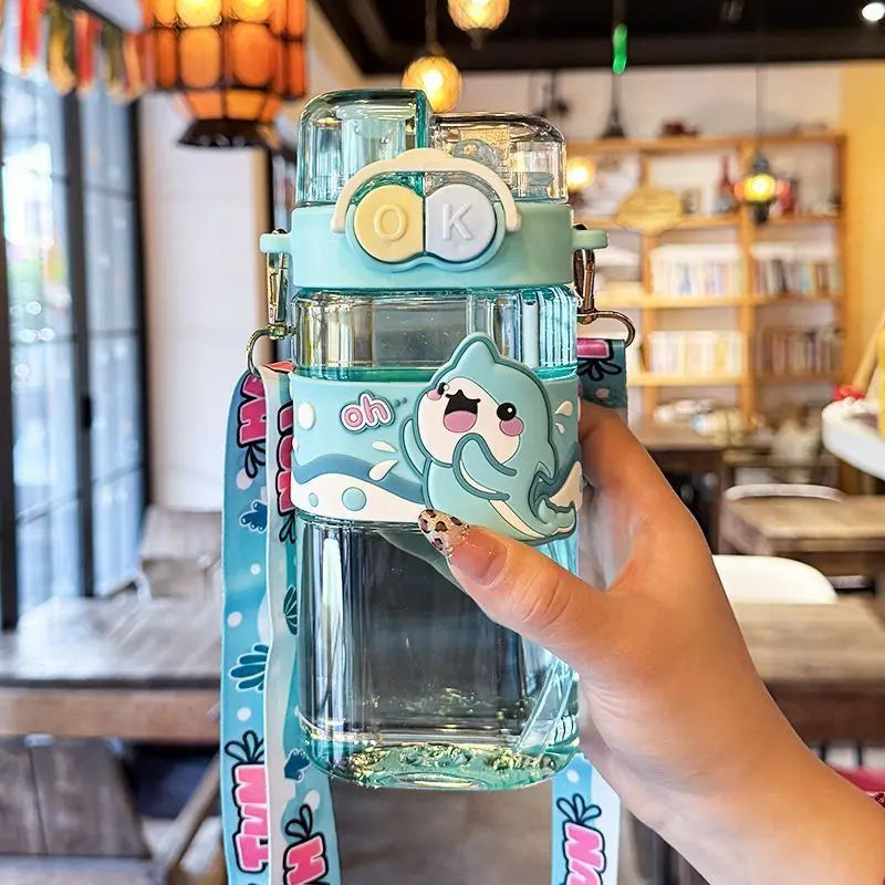 Children's kawaii water bottle with cartoon character design held by a hand in a casual setting.