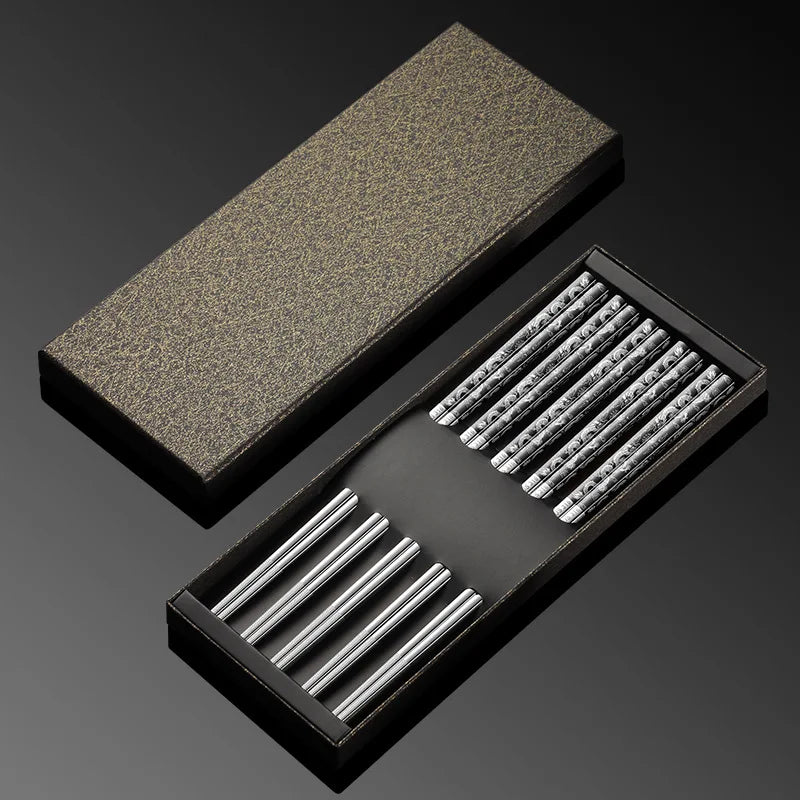 Set of metal kawaii chopsticks in a black box with a textured gray lid on a dark background