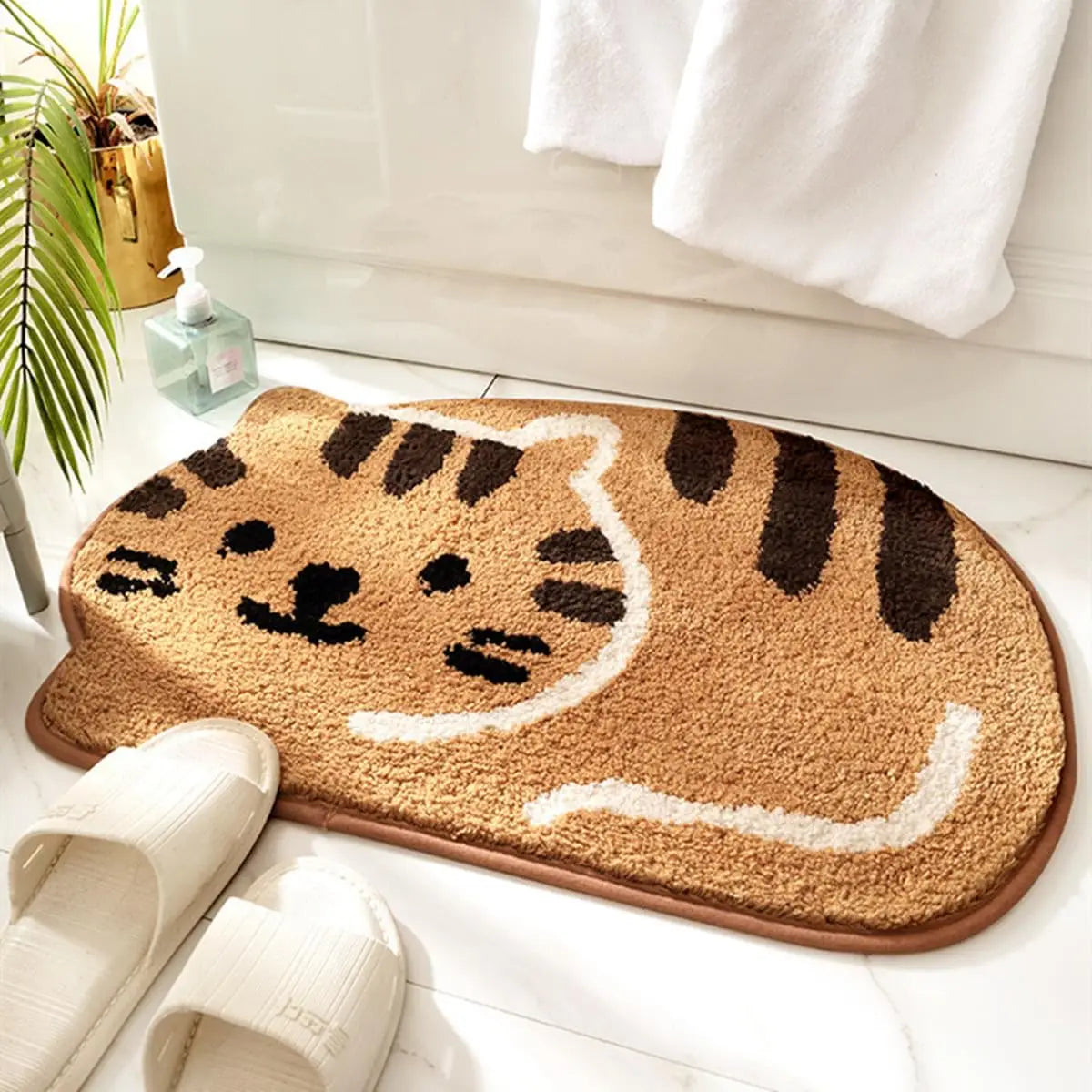Cat-shaped kawaii doormat on a white floor with a plant and towel in the background