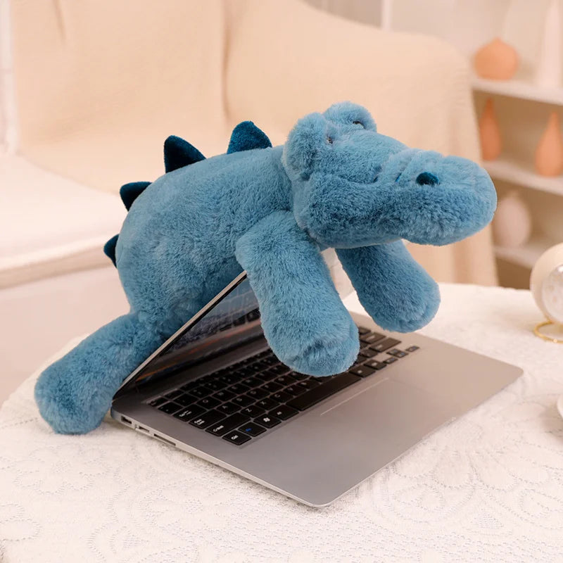 Blue kawaii plush dinosaur on a laptop on a white surface