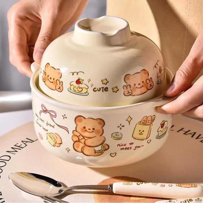 Ceramic kawaii ramen bowl with teddy bear designs and a spoon on a table.