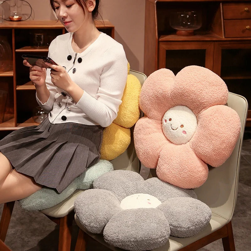 Woman sitting on a chair with flower-shaped kawaii cushions in various colors.