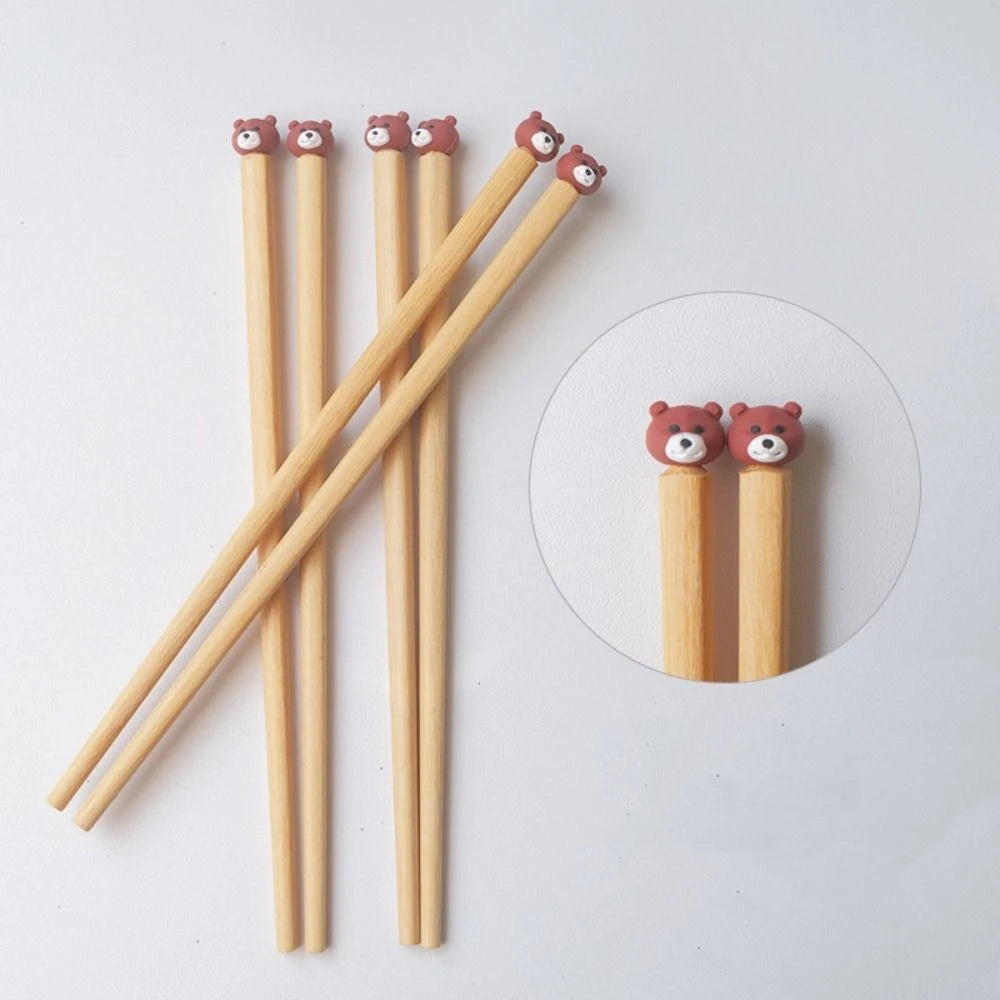 Set of wooden kawaii chopsticks with bear-shaped ends on a white background
