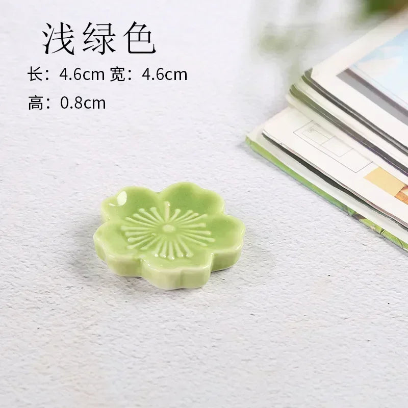 Green ceramic kawaii chopstick holder with floral design on a textured surface