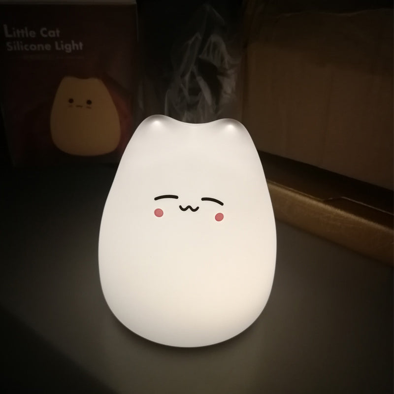 Cat-shaped silicone night light with a kawaii face design on a dark background