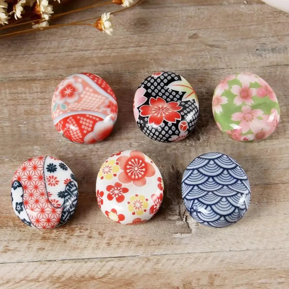 Set of six decorative kawaii chopstick holders with floral and geometric patterns on a wooden surface.