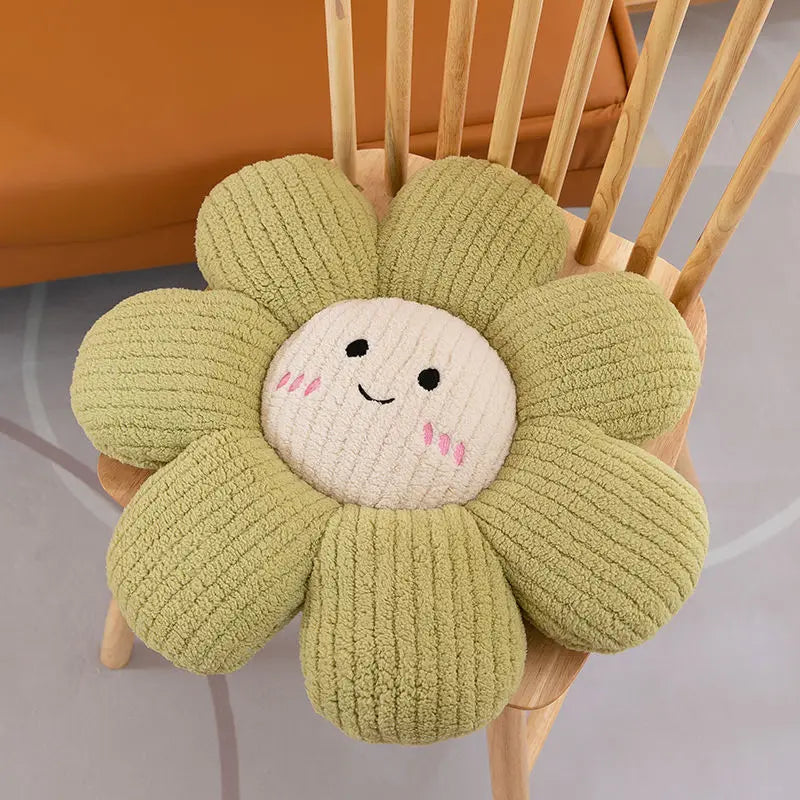 Green flower-shaped kawaii cushion with a smiling face on a wooden chair.