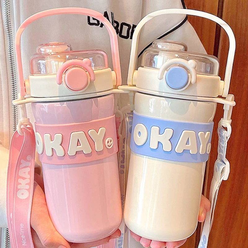 Two colorful kawaii water bottles with 'OKAY' branding held by a person.