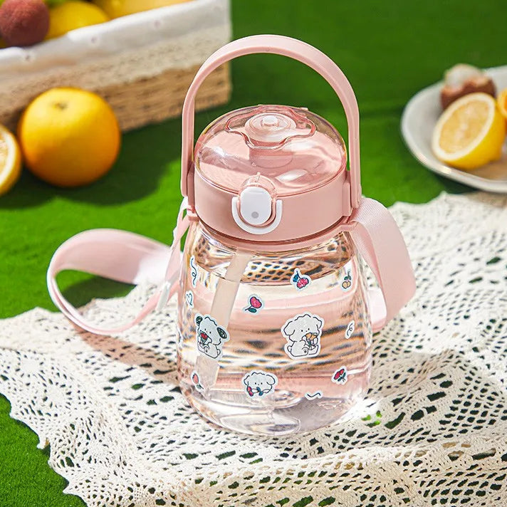 Pink kawaii water bottle with cartoon designs on a green surface with fruits in the background