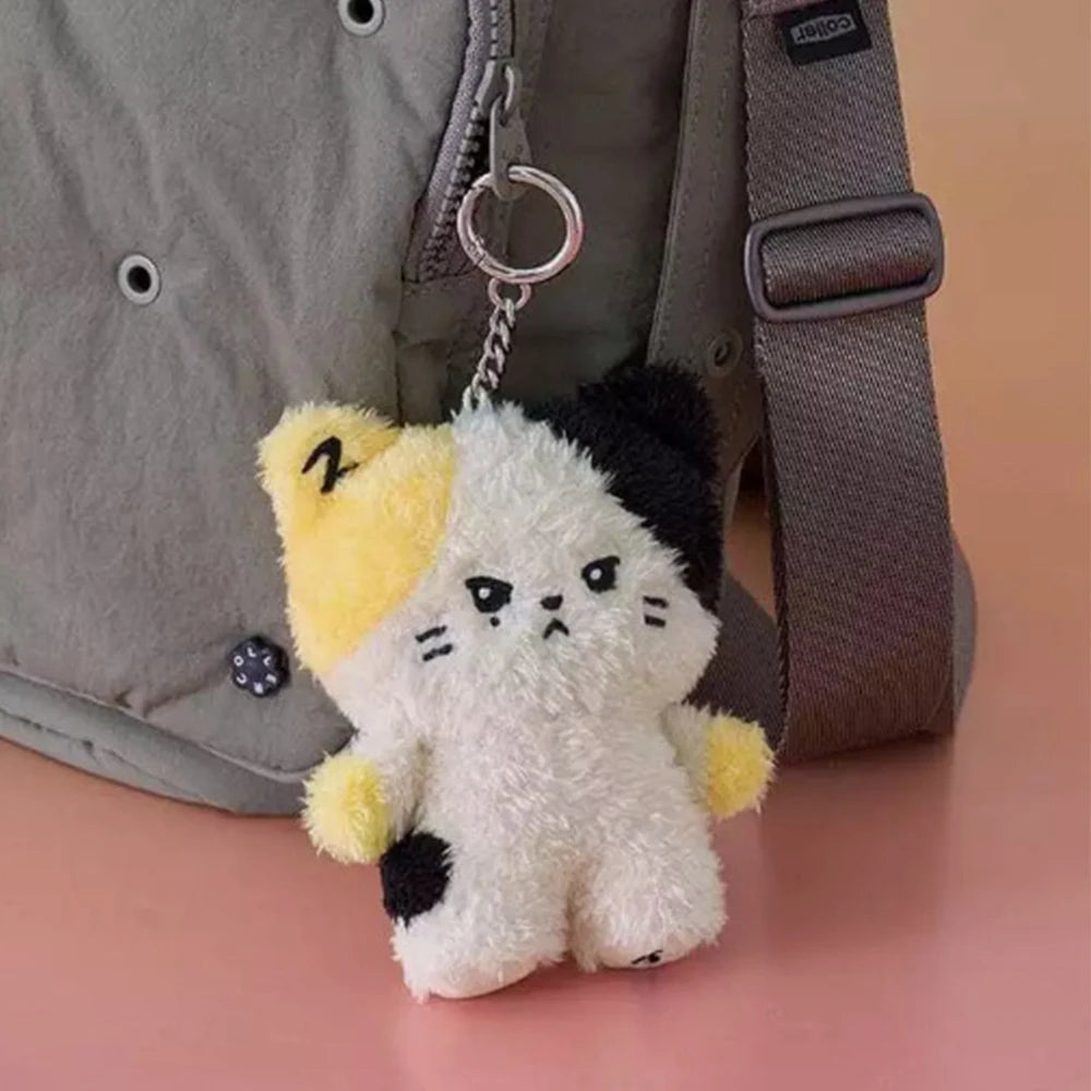 Kawaii plush cat keychain with yellow accents attached to a bag