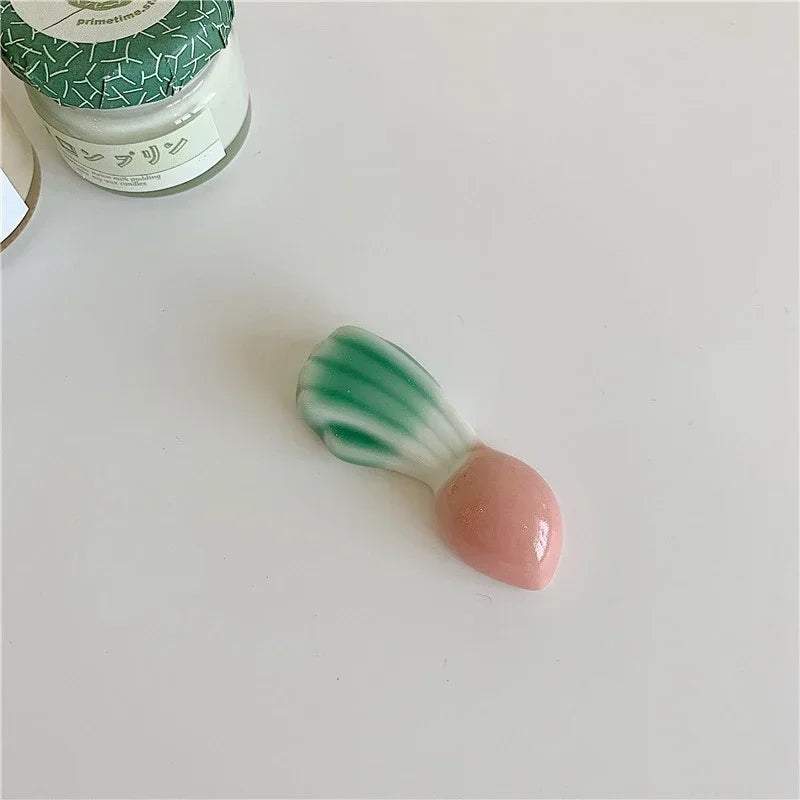 Small ceramic kawaii chopstick holders with green top and pink bottom on a white surface