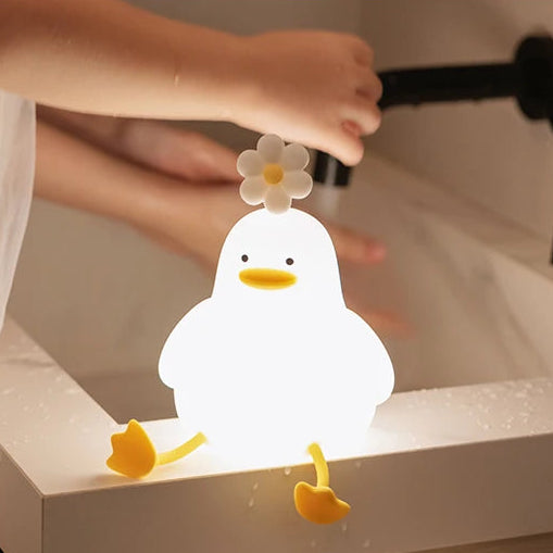 White duck-shaped kawaii night light with a flower on top, held by a person.