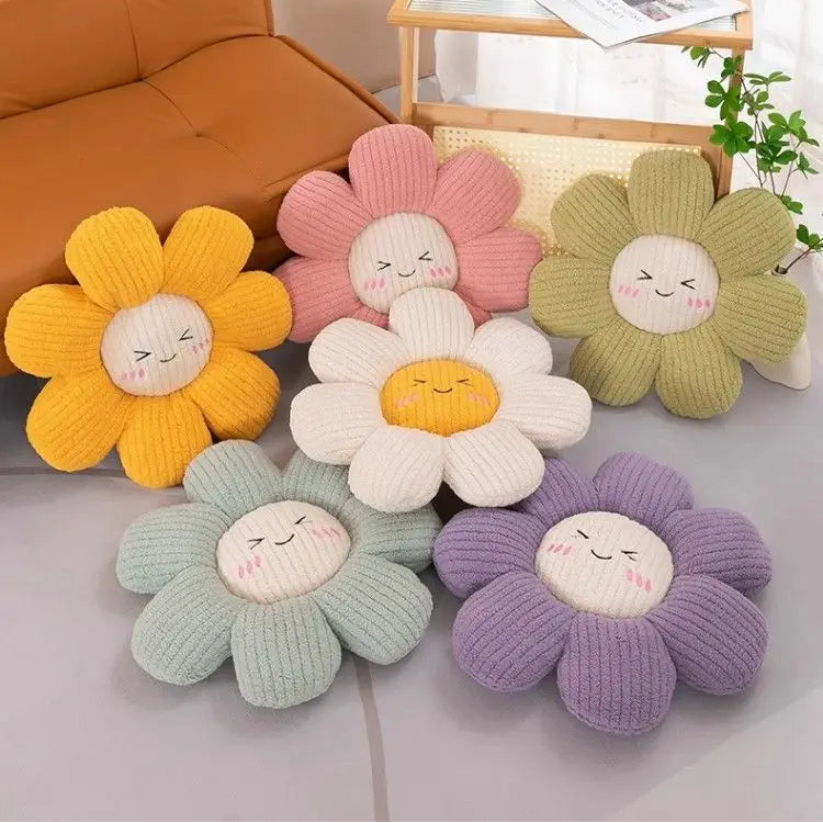 Set of colorful flower-shaped kawaii cushions with smiling faces on a light surface.