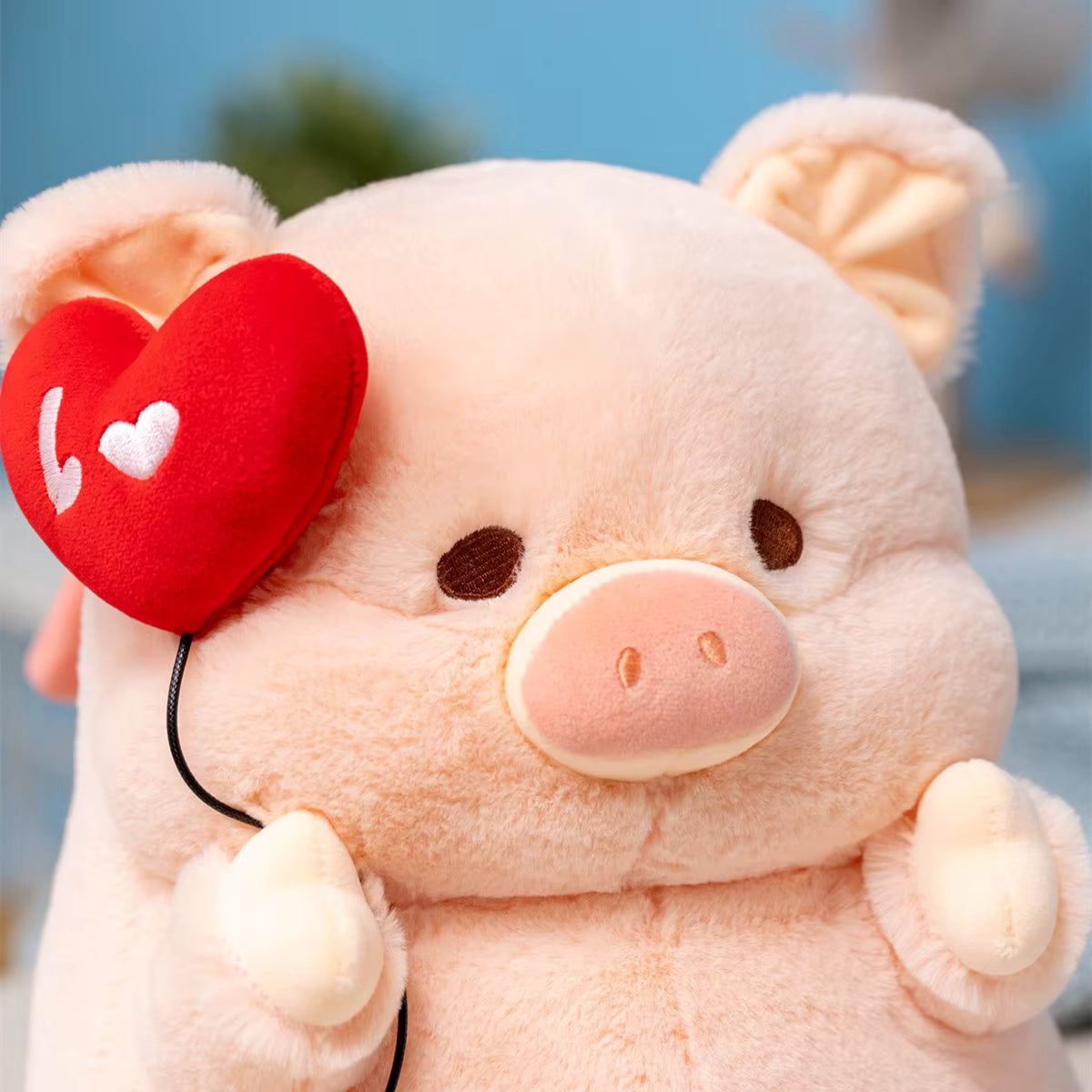 Plush toy pig with a red heart on a blurred outdoor background