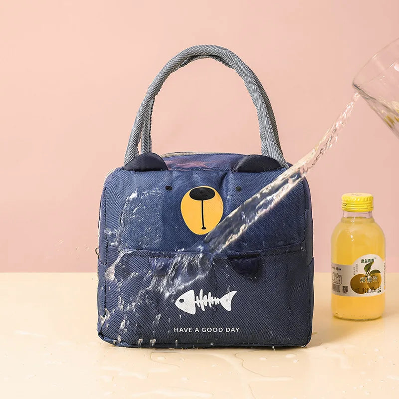 Blue insulated kawaii lunch bag with cartoon design on a pink background