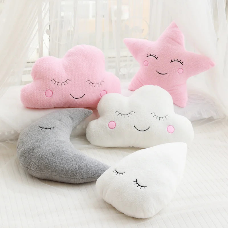 Set of plush cloud, star, moon, and heart-shaped kawaii pillows with smiling faces on a soft surface.