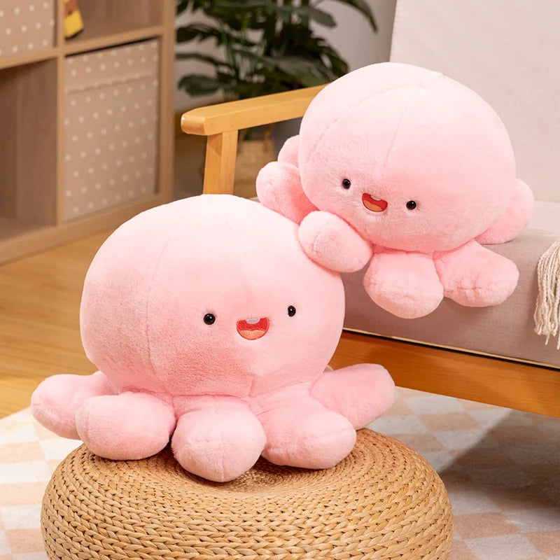 Two pink kawaii plush octopus toys on a woven stool with a blurred indoor background.