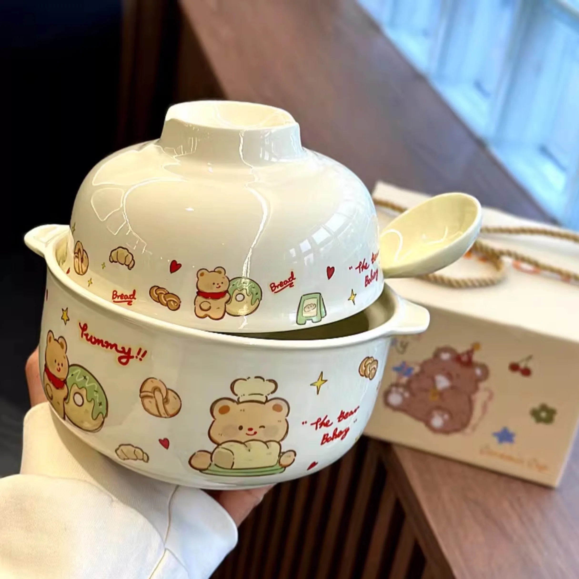 A hand holding a cartoon themed kawaii ramen bowl