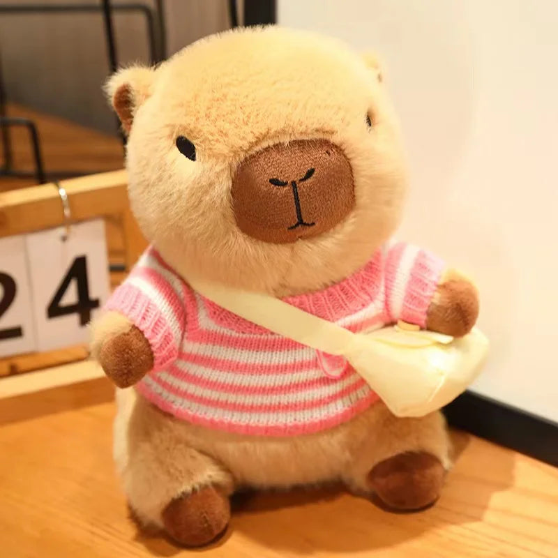 Kawaii plush teddy bear wearing a pink sweater with a white bag on a wooden floor.