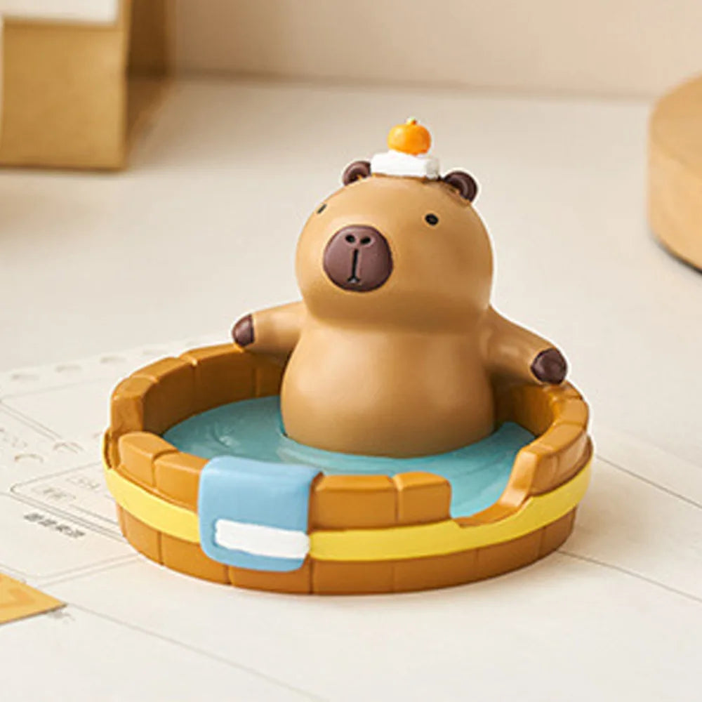 Kawaii capybara phone holder with a small pool on a light surface