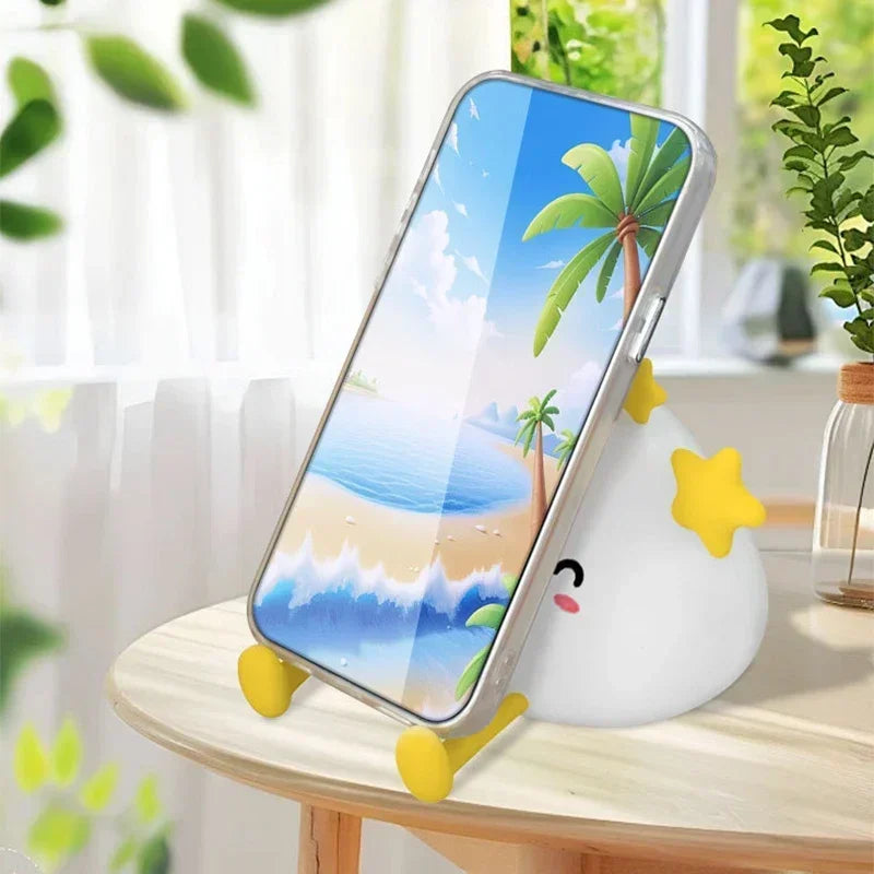 Kawaii phone stand with cartoon design on a table with a beach-themed phone case